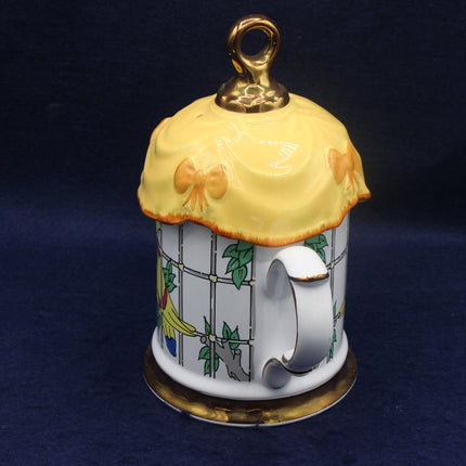 Decorative teapot charm with a yellow lid on a dark blue background