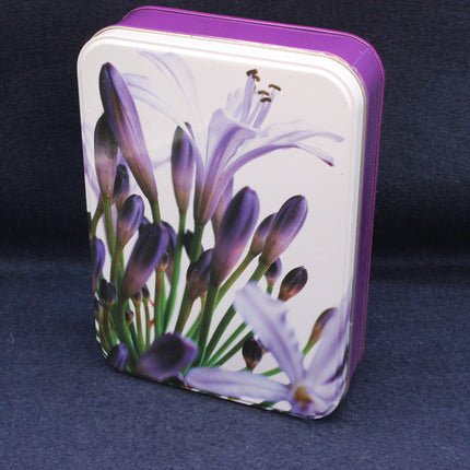 Rectangular tin box with purple floral design on a dark background