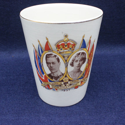 White ceramic cup with royal portraits and coronation design on a blue background