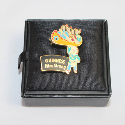Colorful enamel pin with 'Guinness Him Strong' text on a black box