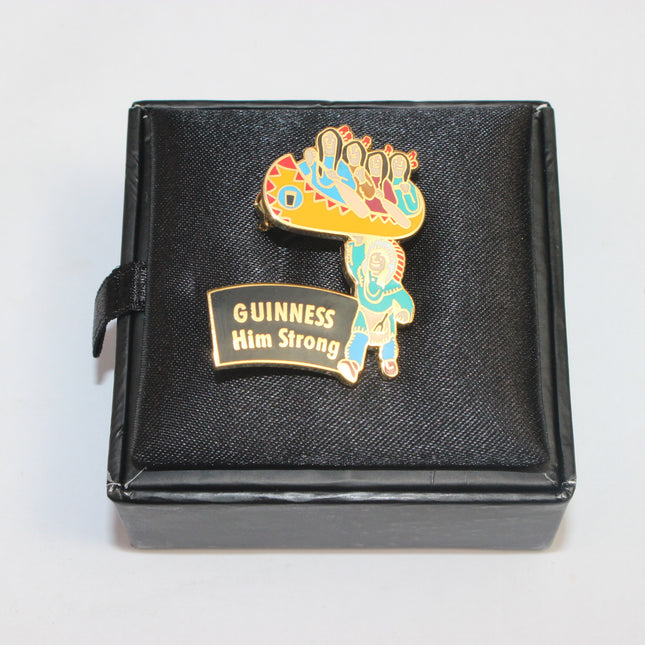 Colorful enamel pin with 'Guinness Him Strong' text on a black box