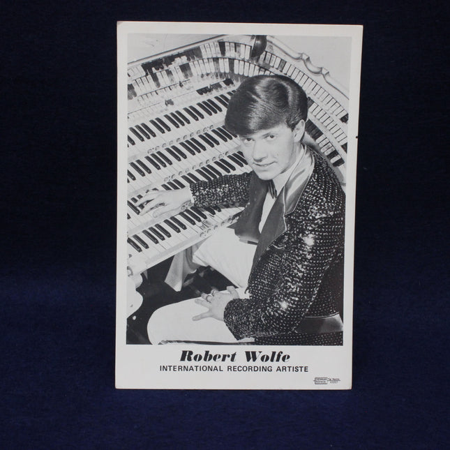 Black and white photo of a man playing an organ with text 'Robert Wolfe International Recording Artist' on a dark background