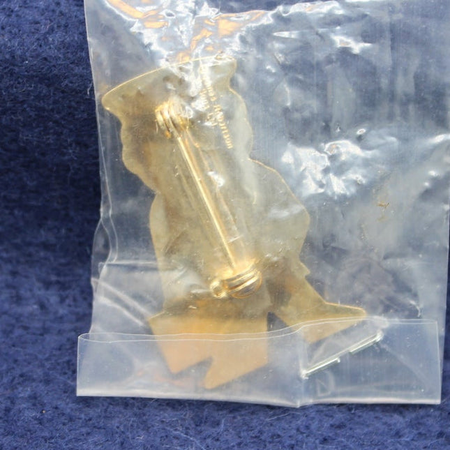 Gold-coloured badge in a clear plastic bag on a blue textured background