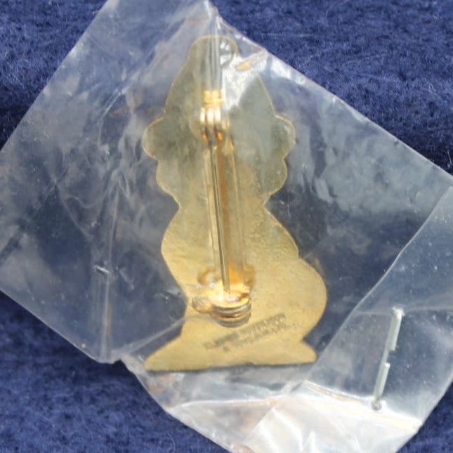 Gold Golly Fireman badge in clear packaging on a blue fabric background