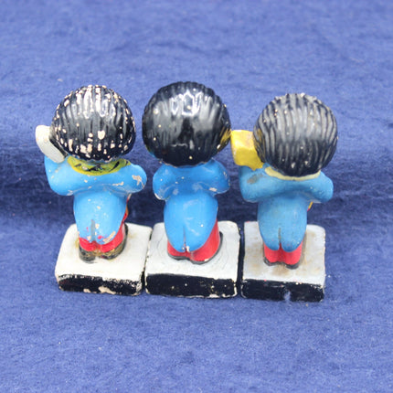 Three small blue characters with black hats sitting on a white block against a blue background
