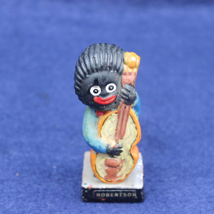 Small figurine of a Golly character with a blue outfit and black hat on a blue background