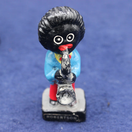 Vintage golliy figurine with a blue outfit and red shoes on a blue background