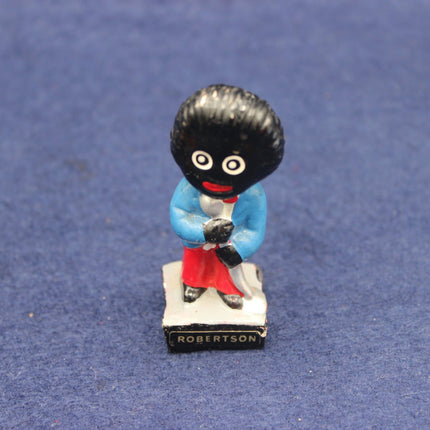 Figurine of a Golly character with a black beret and red shoes on a blue background