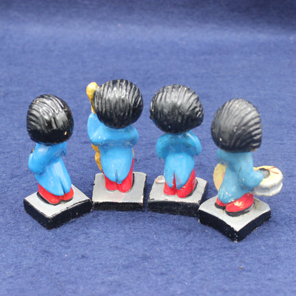 Four small Golly figurines with blue bodies, black hair, and red shoes on a blue background.