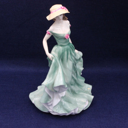 Porcelain figurine of a woman in a green dress and hat on a dark blue background