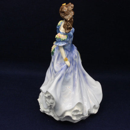 Porcelain figurine of a woman in a blue dress holding a parasol on a dark background