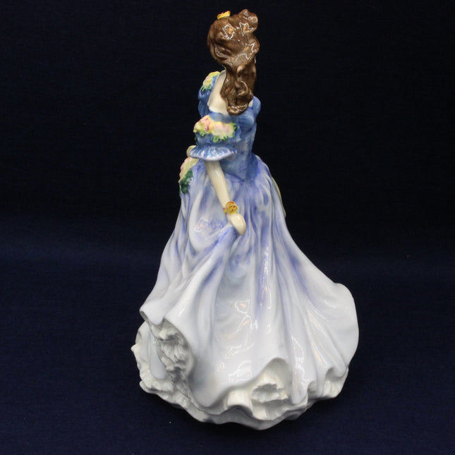 Porcelain figurine of a woman in a blue dress holding a parasol on a dark background