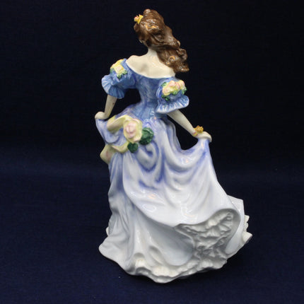 Porcelain figurine of a woman in a blue dress holding flowers on a dark background