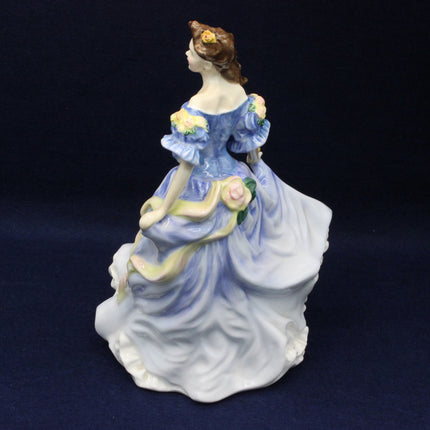 Porcelain figurine of a woman in a blue dress with flowers on a dark background