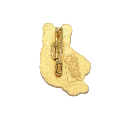A small gold Rupert Bear shaped pin or charm with a metal clasp and a small attached tag, photographed on a plain light gray background.