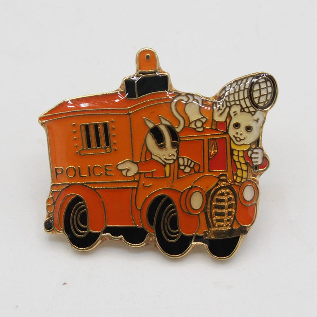 A cartoon-style enamel pin shaped like an orange police truck, featuring a skeleton driver and a skull-shaped siren, photographed on a plain white background.