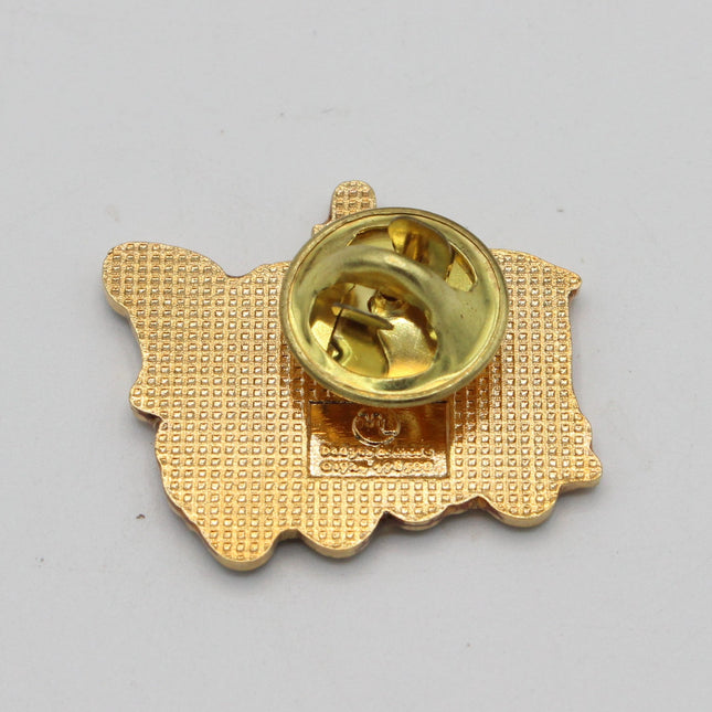 Gold metal lapel pin backing with a textured pattern and a shiny gold pin clasp, photographed on a plain light gray background.