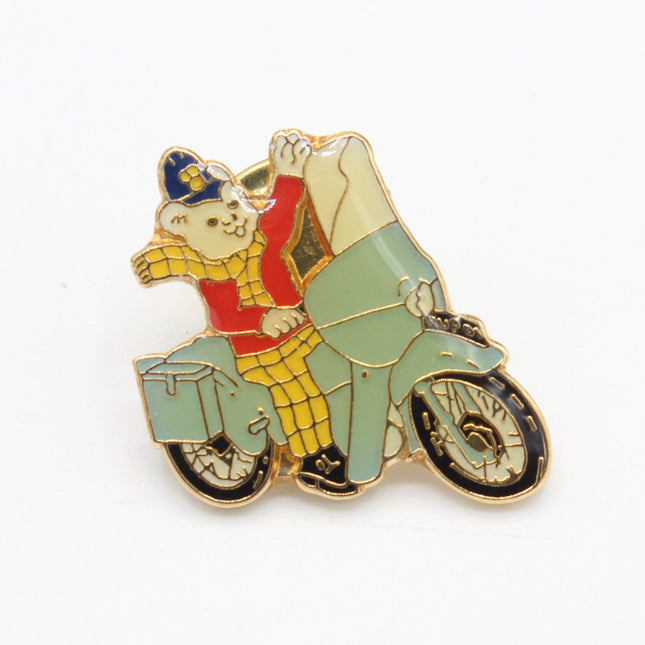 Rupert Bear enamel badge featuring Rupert riding a motorcycle. 22mm high. Nostalgic vintage Rupert collectible.