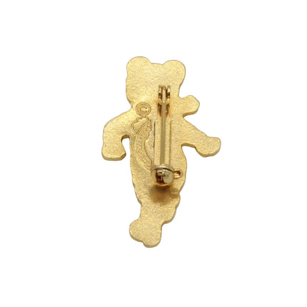 A small gold bear-shaped pin with a visible safety pin clasp on the back, photographed against a plain light gray background.