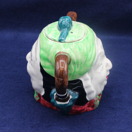 Decorative teapot with a green lid and wooden handle on a blue background