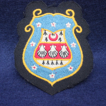 Embroidered patch with a shield design on a blue fabric background