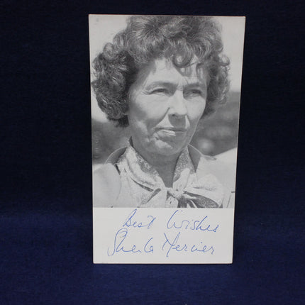 Black and white photo of a woman with curly hair, signed by Sheila Mercier, on a dark background.