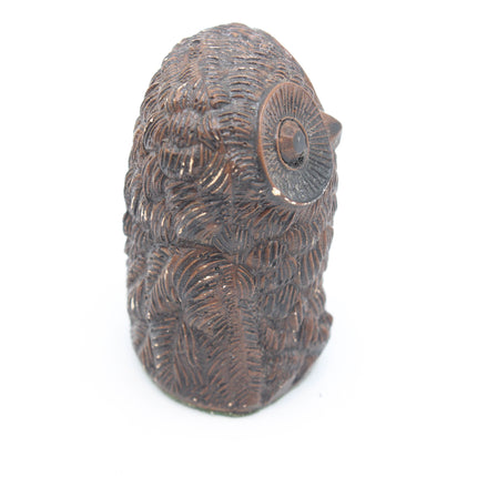 A carved brown wooden owl figurine with detailed feather textures and a prominent eye, shown against a plain white background.