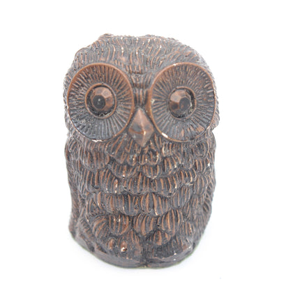 A small owl figurine with textured feathers and large round eyes, finished in a dark metallic bronze or copper-like finish, shown against a plain white background.