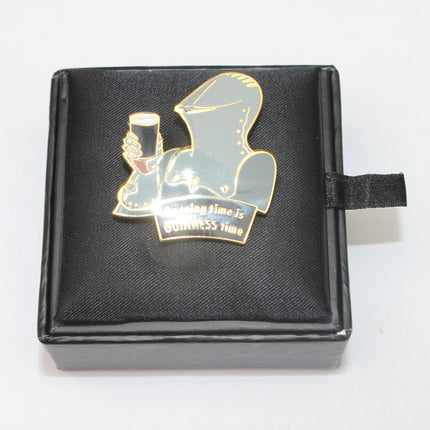 Pin with a hooded figure holding a glass on a black box