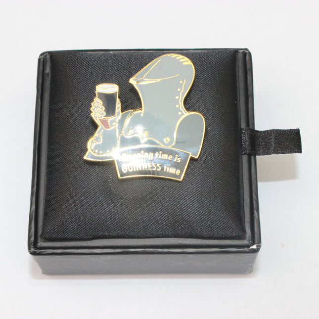 Pin with a hooded figure holding a glass on a black box