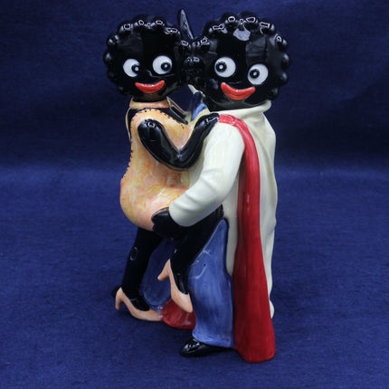 Figurine of Gollies with blackface makeup holding a child on a blue background