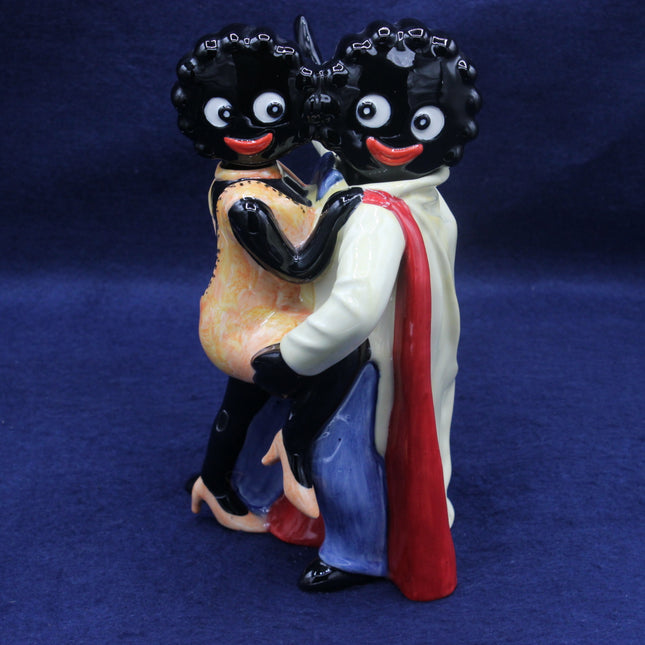 Figurine of Gollies with blackface makeup holding a child on a blue background