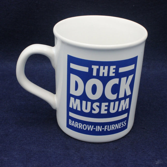 White mug with text 'The Dock Museum Barrow-in-Furness' on a dark blue background