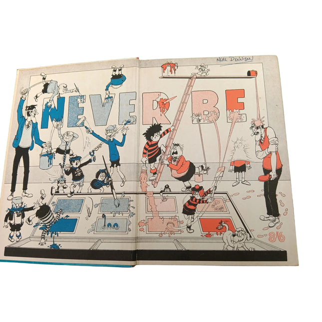 An open vintage comic book or art book spread, featuring a hand-drawn cartoon illustration of characters painting the word 'BEVER' in large letters. The page is photographed from above on a green surface.