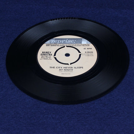 Vinyl record with Nancy Sinatra The City Never Sleeps At Night on a blue textured background