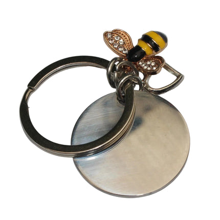 Keychain with bee-shaped charm and silver disc on a light gray background
