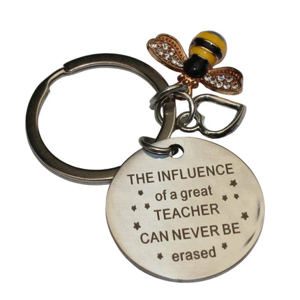 Keychain with bee charm and engraved message on a gray background