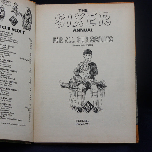 Open book titled 'The Sixer Annual for All Cub Scouts' with a illustration of a boy and dog on the cover page.
