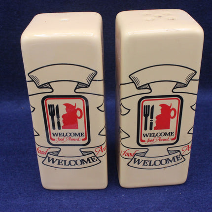 Two ceramic salt and pepper shakers with a 'Welcome Food Award' logo on a blue background.