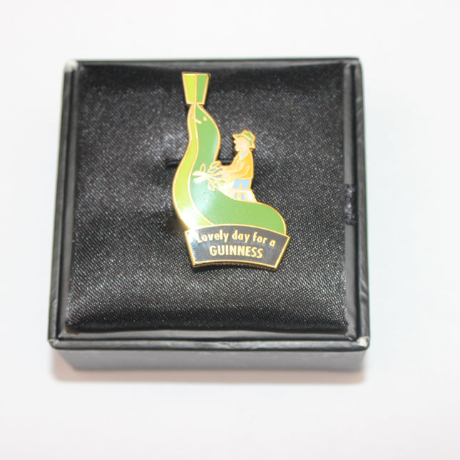 Guinness-themed lapel pin in a black box on a white background