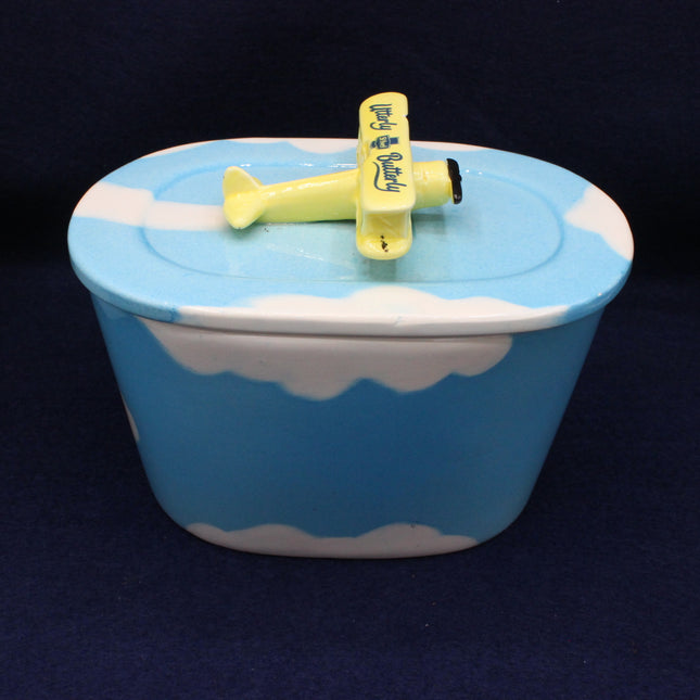 Blue container with white cloud design and yellow airplane on a dark background