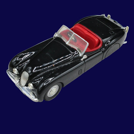 Black model Jaguar car with red interior on a light gray background