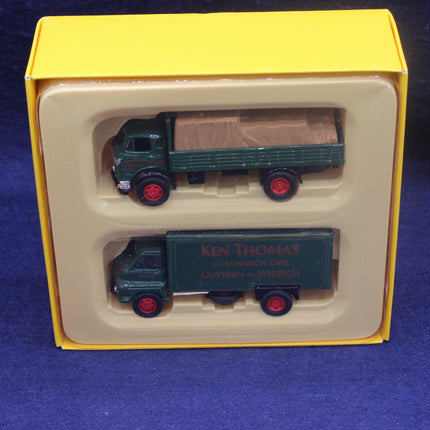 Two toy trucks in a yellow and beige box on a blue background