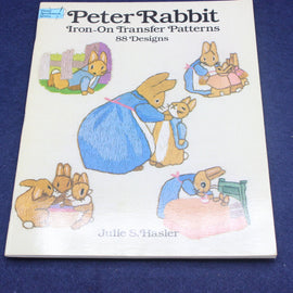 Book titled 'Peter Rabbit Iron-On Transfer Patterns' with illustrations of rabbits on a blue background