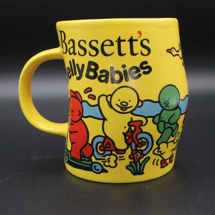 Yellow mug with cartoon characters and 'Bassetts Jelly Babies' text on a dark background