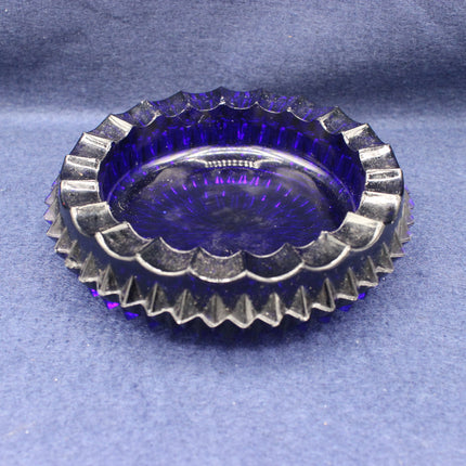 Round purple glass vintage ashtray with textured rim on a grey background
