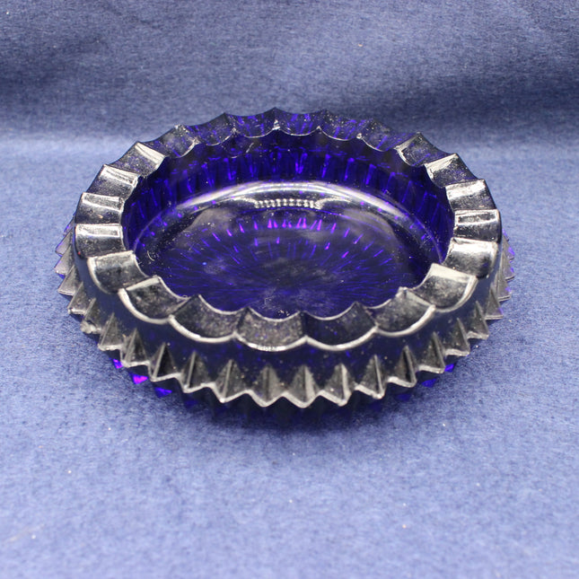 Round purple glass vintage ashtray with textured rim on a grey background