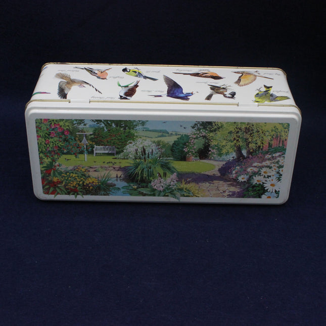 Decorative box with bird illustrations on top and a garden scene below, against a dark background.