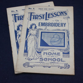 Vintage book titled 'First Lessons in Embroidery' on a dark background