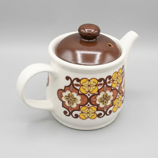 Decorative ceramic teapot with floral patterns on a blue background